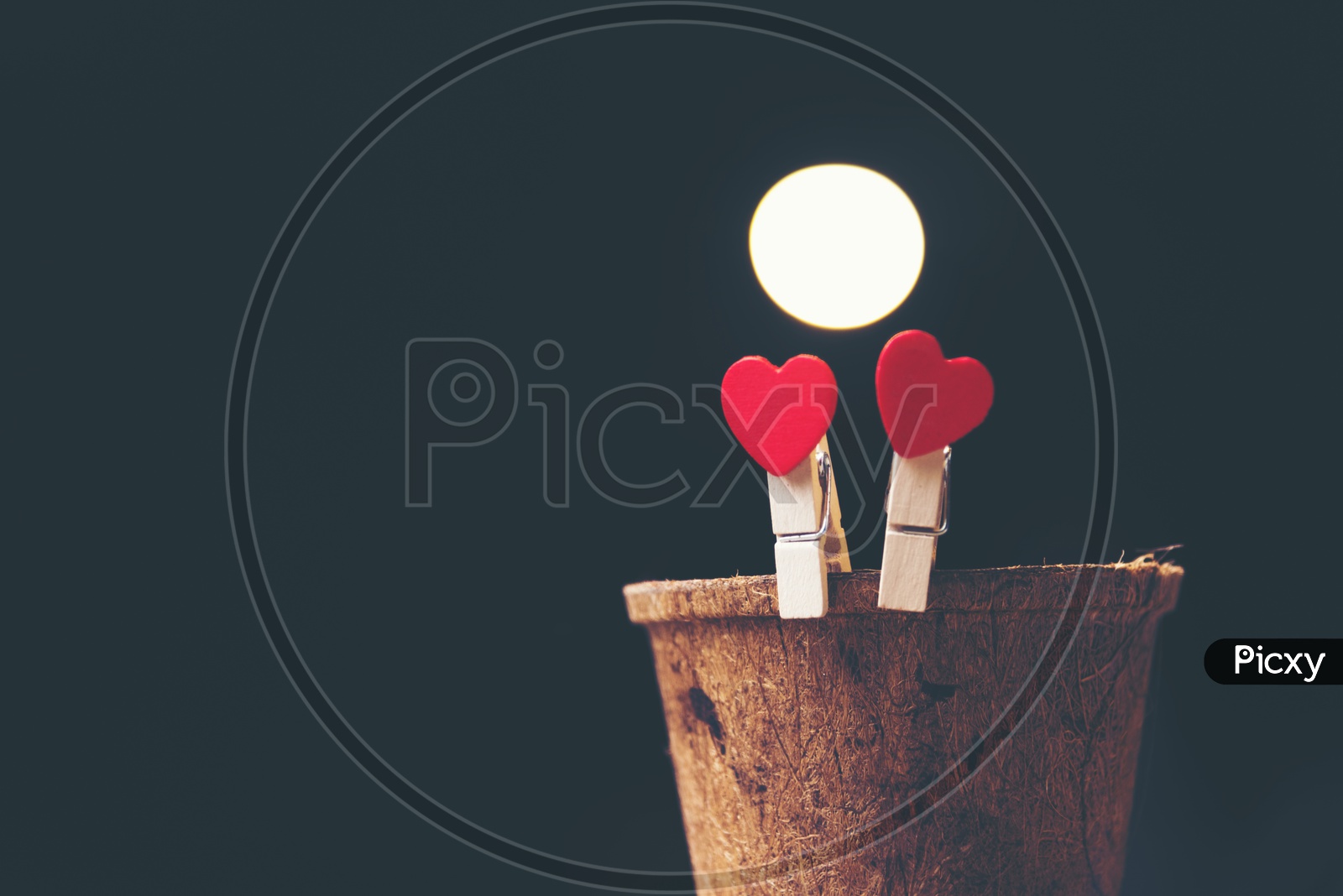 Heart shaped wooden clips on a wooden cup with black background