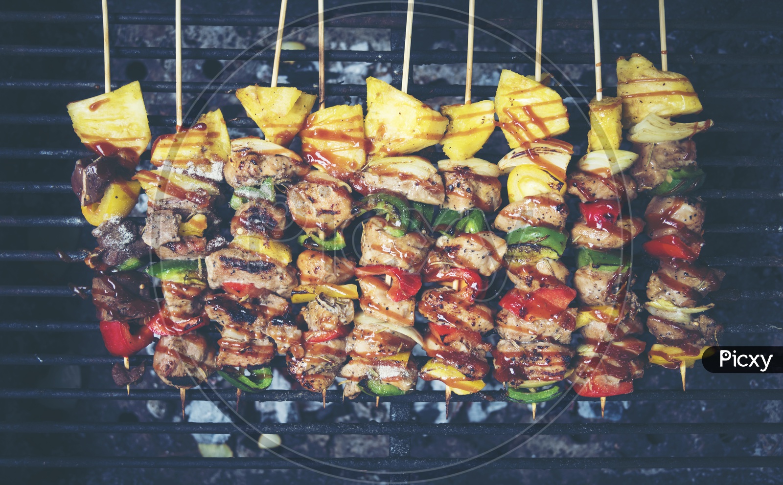 Grilled beef and vegetable BBQ skewers on the black background, top view, vintage filter image