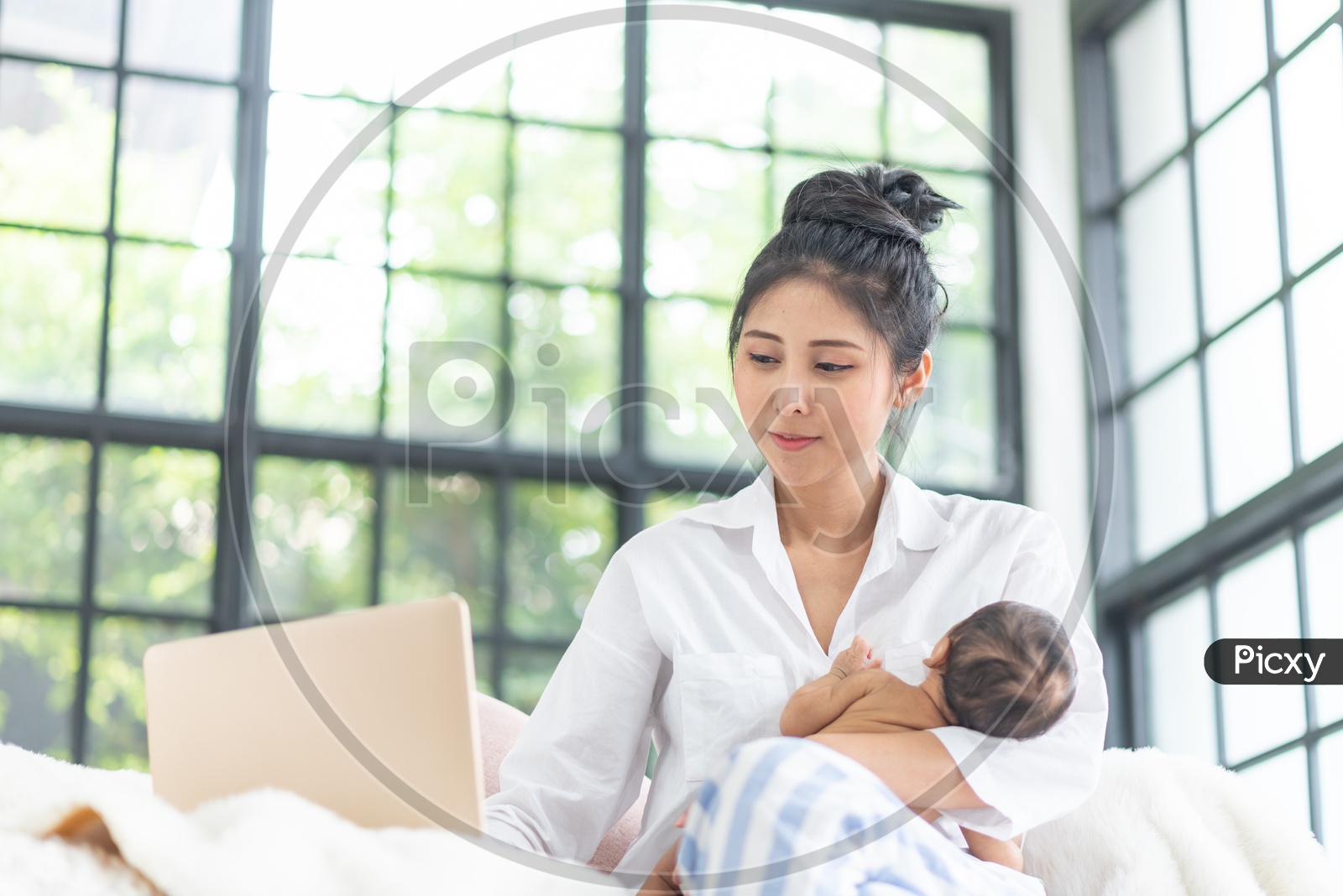 Asian Mother is raising a baby while working from home.