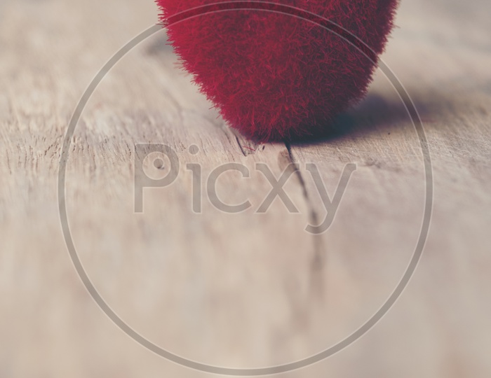 Close up of soft fur heart shaped toy on a wooden background