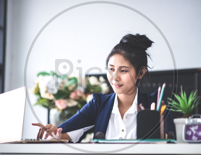 A Young Asian Businesswoman working on Laptop at Workplace, business people concept