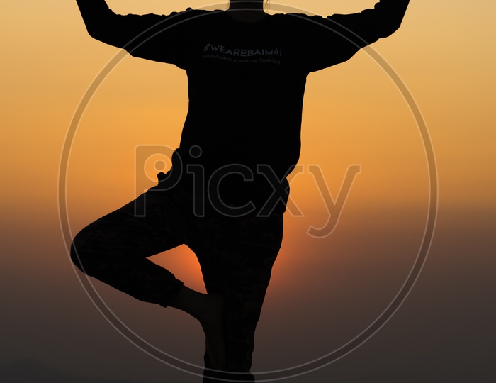 Silhouette  Of People Practicing  Yoga Over Sunset Sky In Background