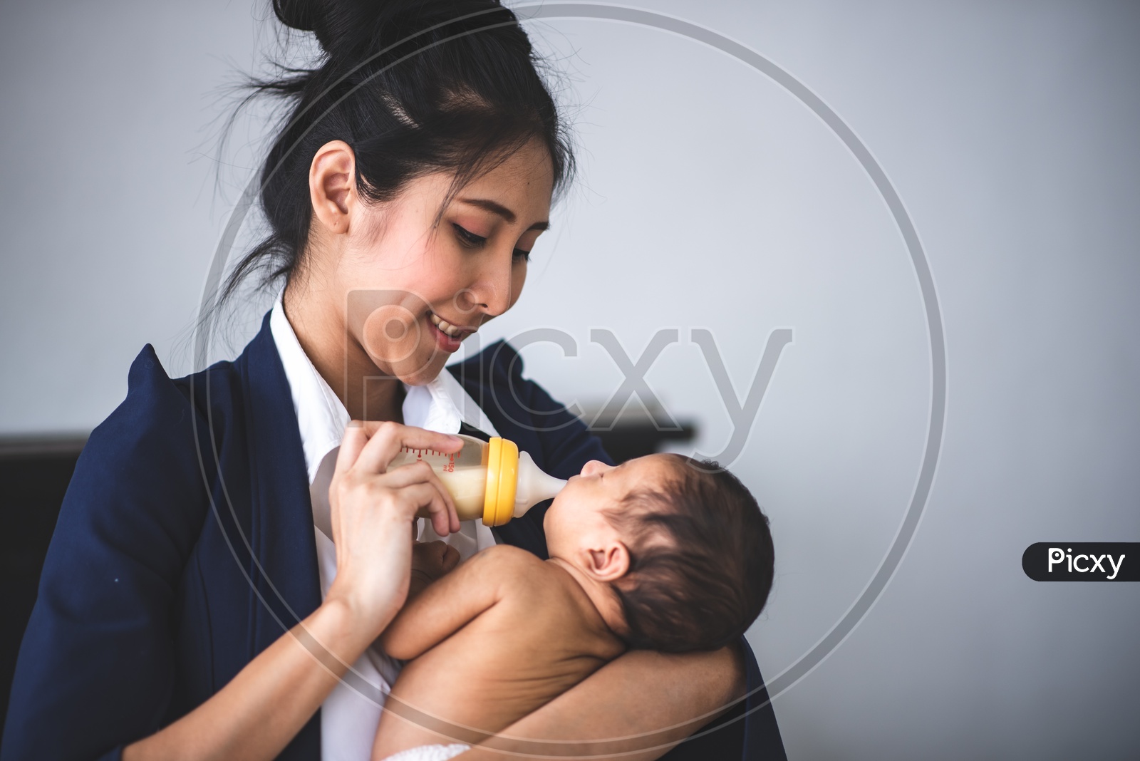 Young Asian Mother Feeding her baby at the workplace