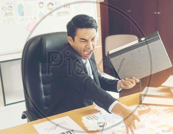 Concept of stress and frustration of a businessman throwing a crumpled paper and file