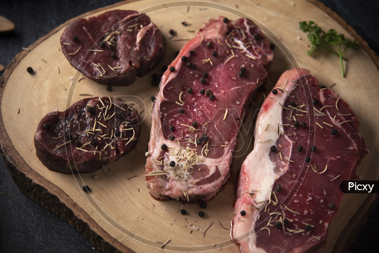 Fresh raw Prime Black Angus beef steaks on wooden board: Tenderloin, Denver Cut, Striploin, Rib Eye