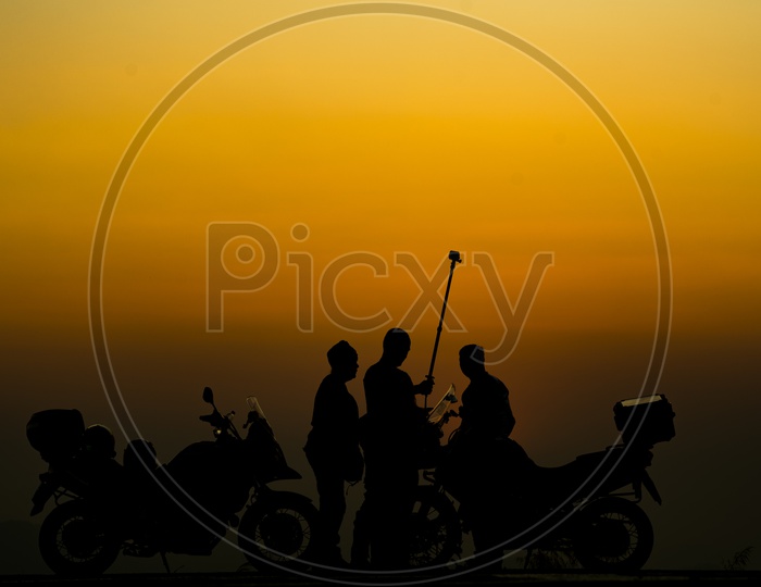 Silhouette Of Group Of Young Adventure Travelers Over sunset Background