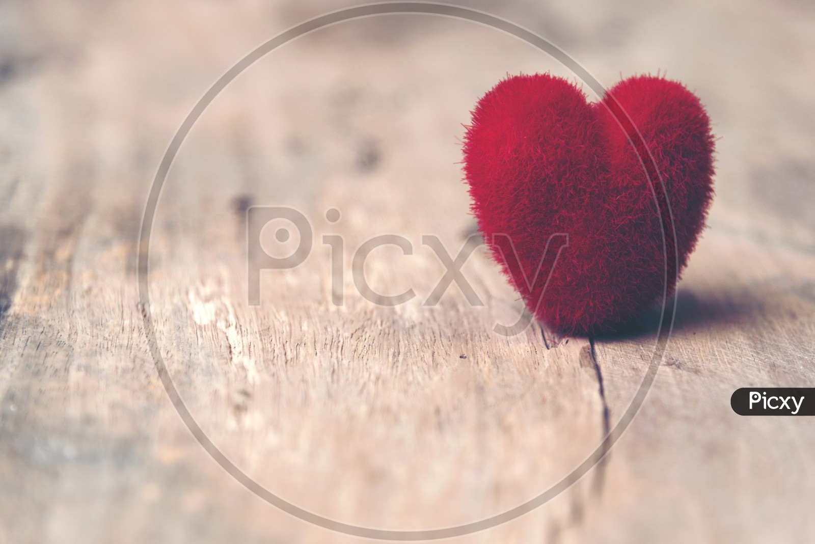 Close up of soft fur heart shaped toy with wooden background