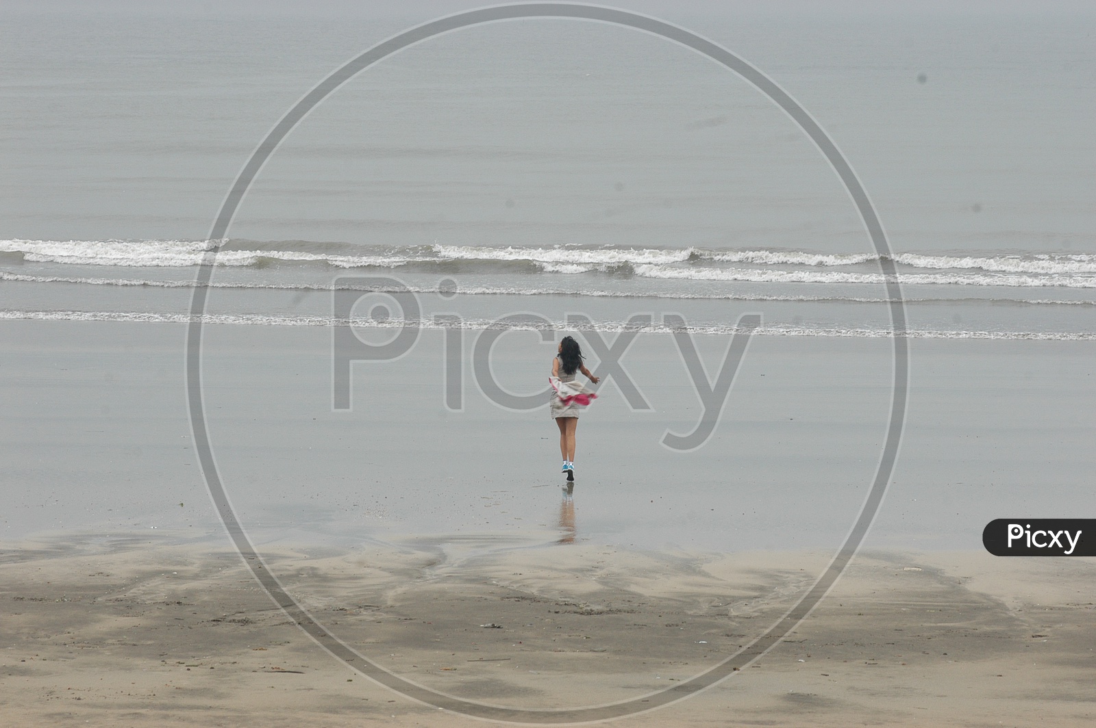 A Girl running with shoes at the beach