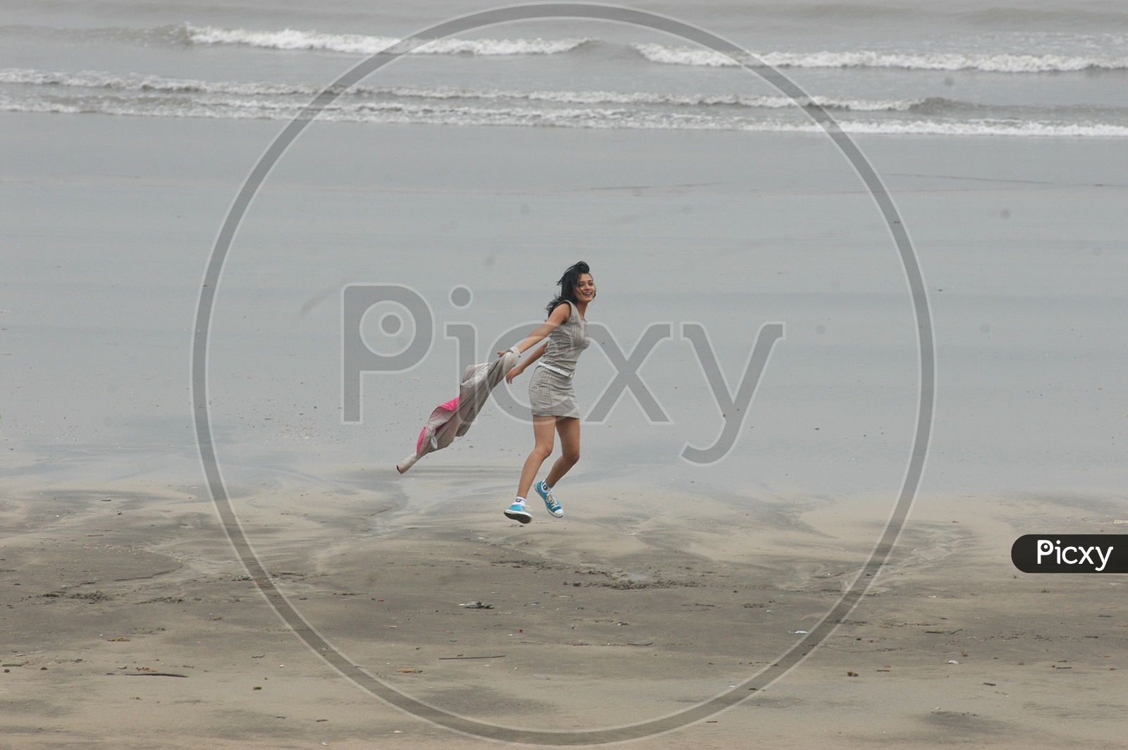 A Girl running holding her jacket at the beach