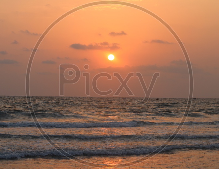 Sunset Over a Beach With bright Sun And Waves Striking Shore