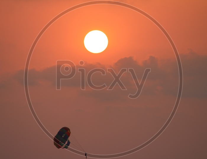 Paragliding Over Sea in Goa With Bright round Sun In Background