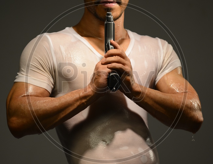 Drenched Indian Muscular Man pointing a gun to his face