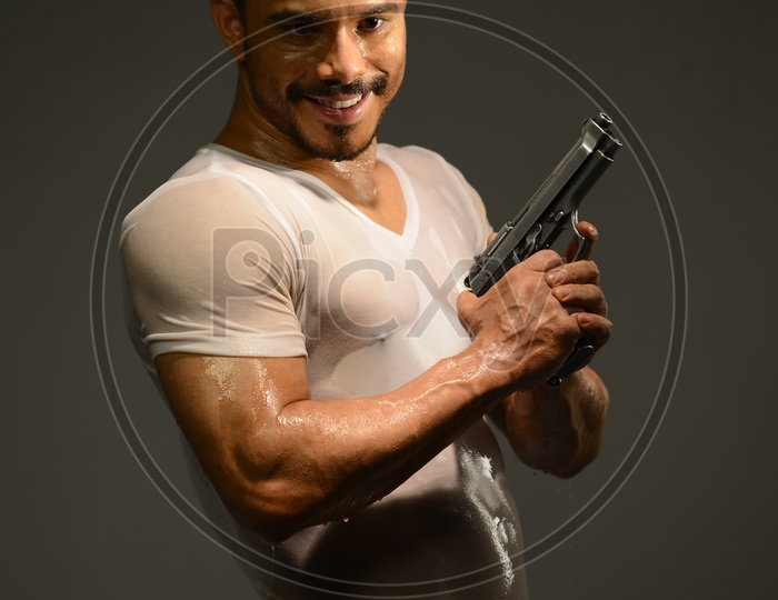 Drenched Indian Muscular Man holding a revolver