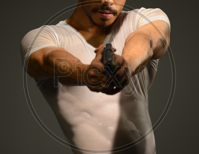 Drenched Indian Muscular Man aiming with a pistol
