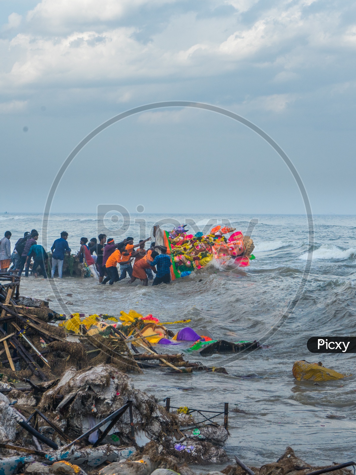 People pushing lord ganesha idol into the sea and waste on the shore
