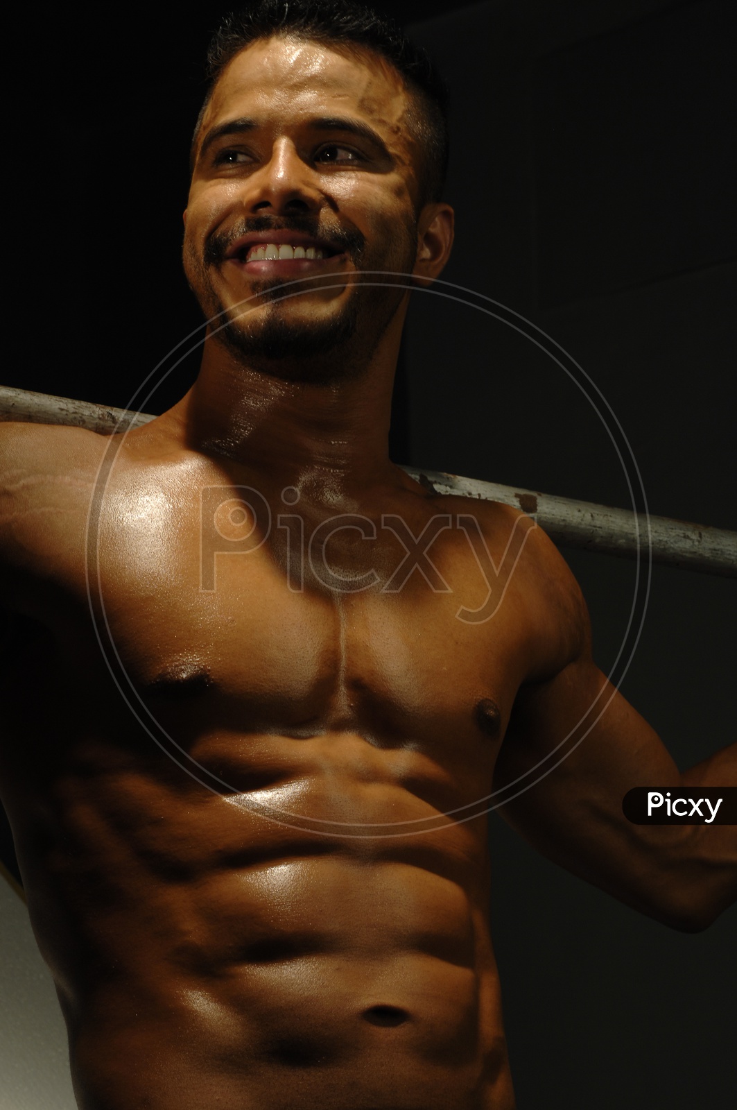 Indian Muscular Man smiling holding a Rod