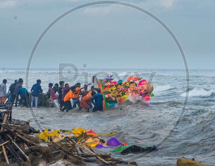 People pushing lord ganesha idol into the sea and waste on the shore