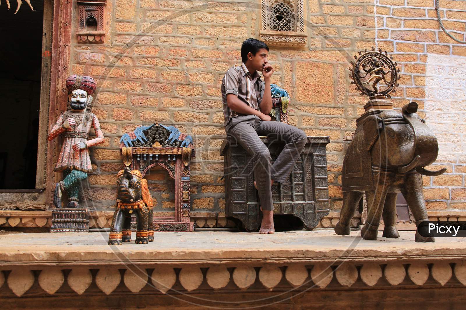 A Rajasthani Boy Sitting At an  Road Side Antique Vendors Stall In Jaisalmer , Rajasthan