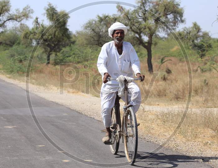 Rajasthani man wearing white turban riding bicycle