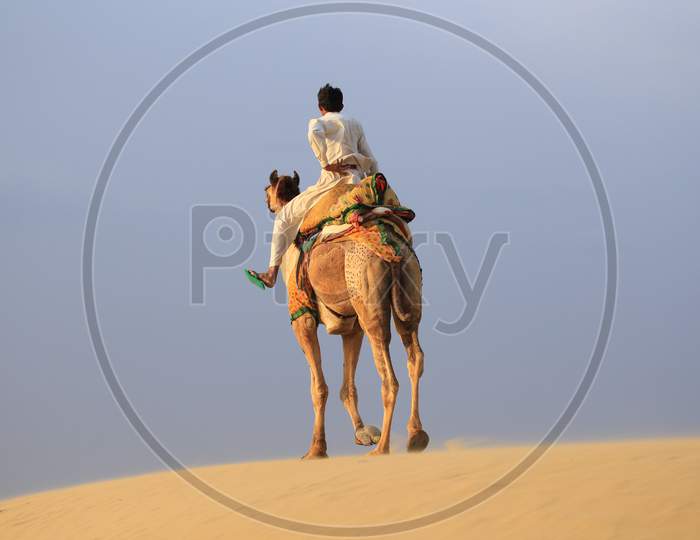 A Man riding a camel in the desert