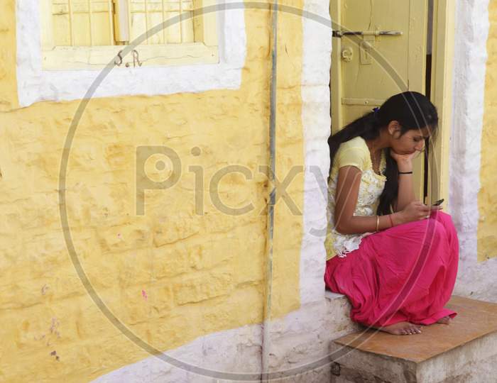 Indian girl sitting at the entrance using mobile