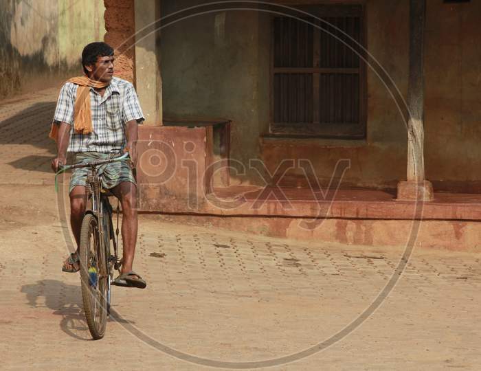An Indian man wearing scarf riding bicycle