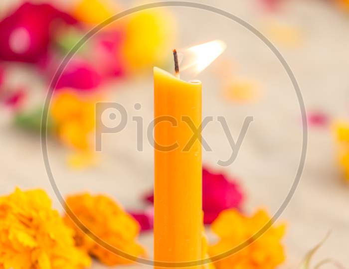 Candle On Desert Sand With Flowers  Scattered