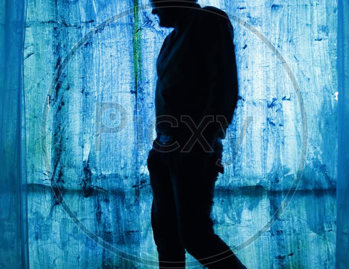 Silhoutte of a man posing with hands in his pocket