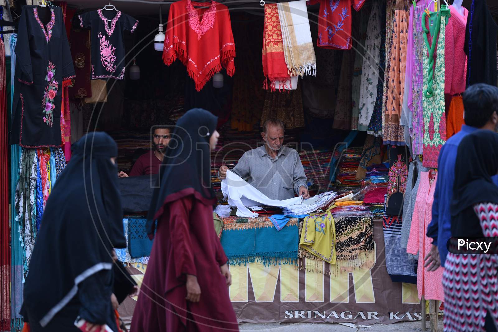 women pass by a Kashmiri shawls stall in Numaish Exhibition.