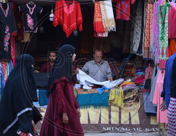 women pass by a Kashmiri shawls stall in Numaish Exhibition.