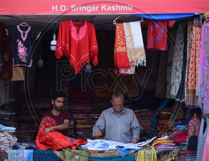 A Kashmiri Textile shop owner folding shawls in his stall at Numaish Exhibition