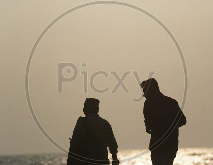 Silhouette Of People In a Beach With Sunset Sky In Background