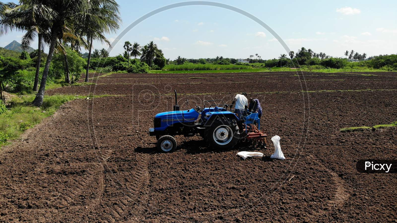 A Farmer Ploughing Agricultural Land With Tractor