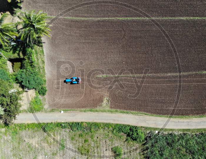Drone Shot Of  A Farmer Ploughing Agricultural Land With Tractor