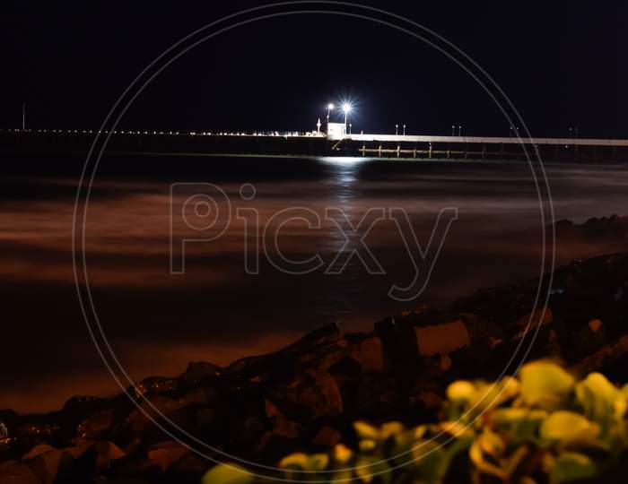 Long view of a bridge in the night beside a beach