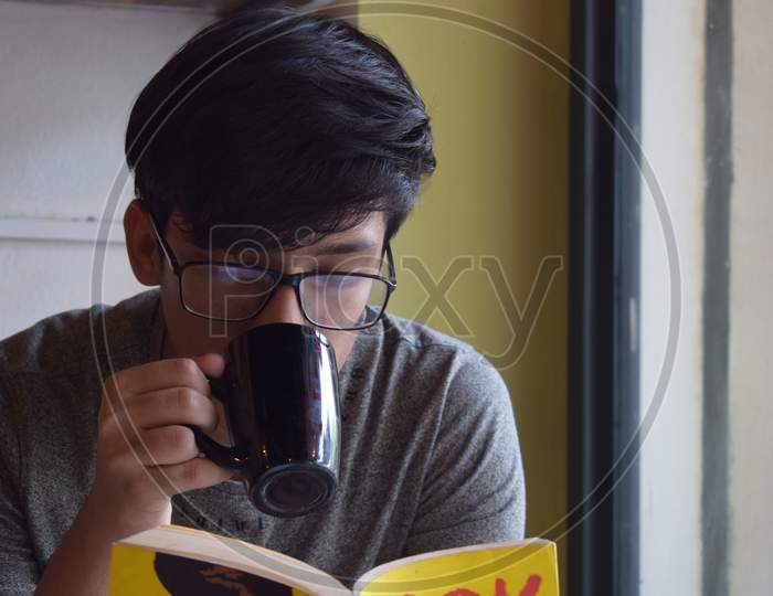 A Man Having Coffee And Reading Book