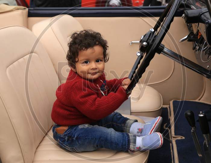 A Little kid smiling holding the steering wheel