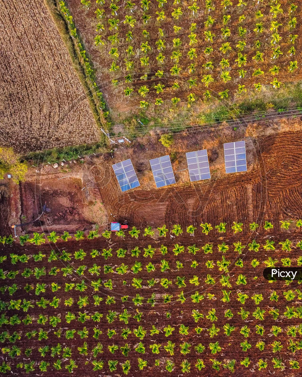 Aerial Shot of Tractor working in a field equipped with Solar Panels