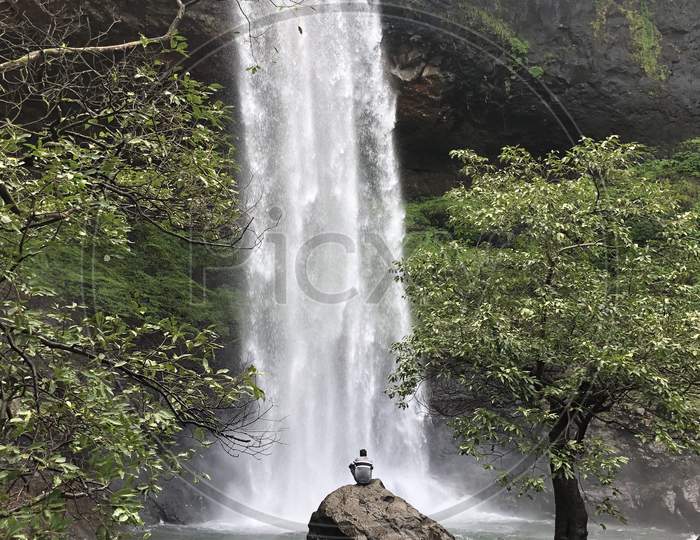 A Man Sitting At a Waterfalls