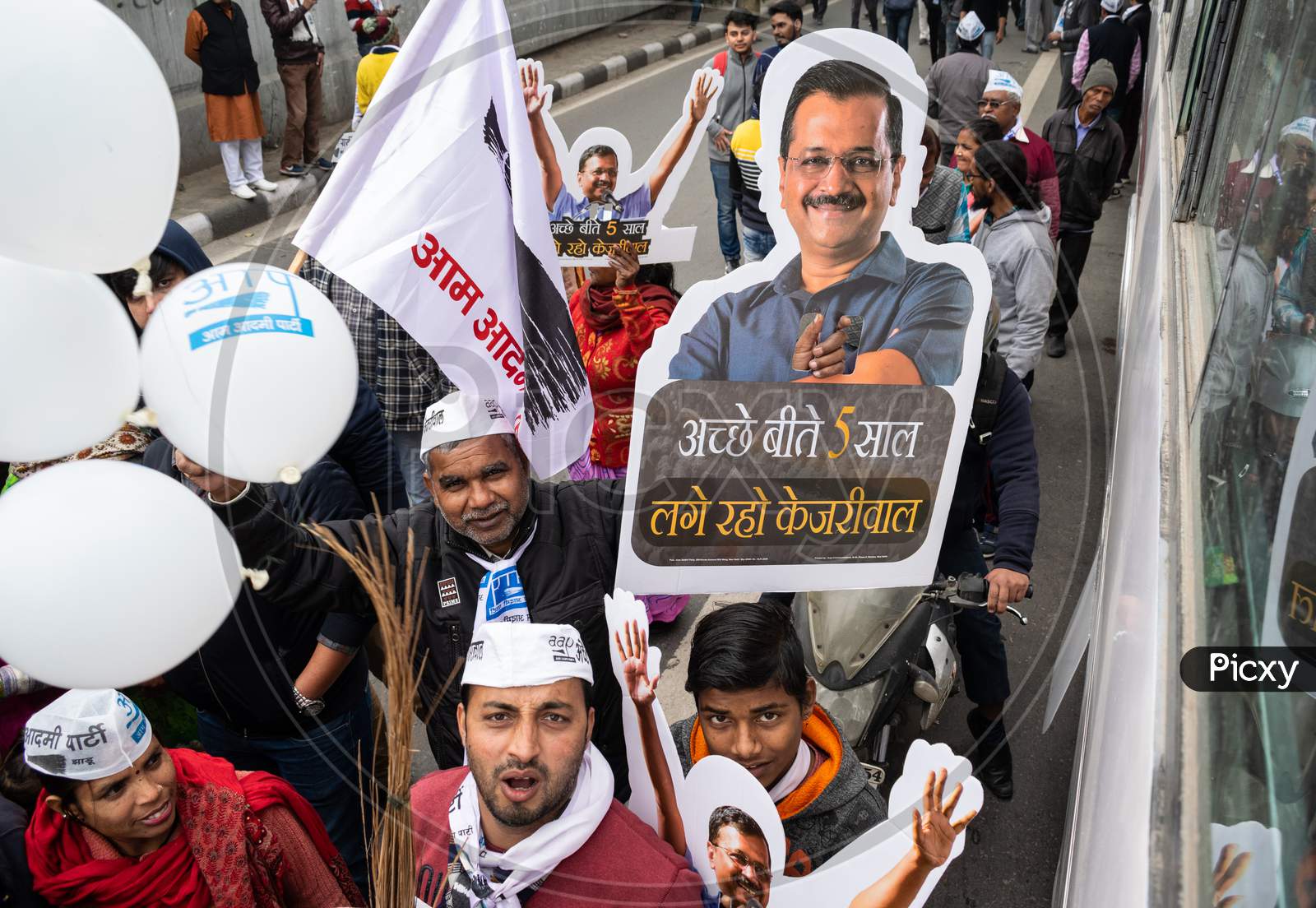 Aam Aadmi Party AAP supporter holding cutout of Arvind Kejriwal, flag and AAP electoral symbol Broom during a rally for Delhi Assembly Election