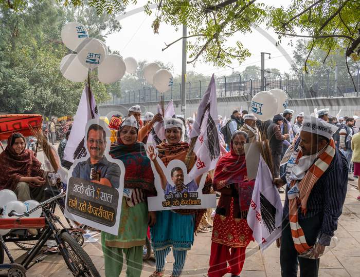 Aam Aadmi Party AAP supporters holding cutout of Arvind Kejriwal and electoral symbol for AAP during a rally for Delhi Assembly Election