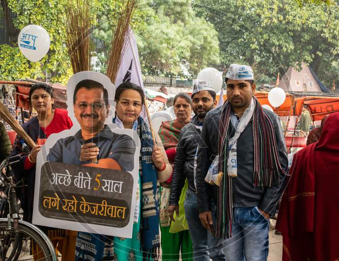 Aam Aadmi Party AAP supporters holding cutout of Arvind Kejriwal, flag and AAP electoral symbol Broom during a rally for Delhi Assembly Election