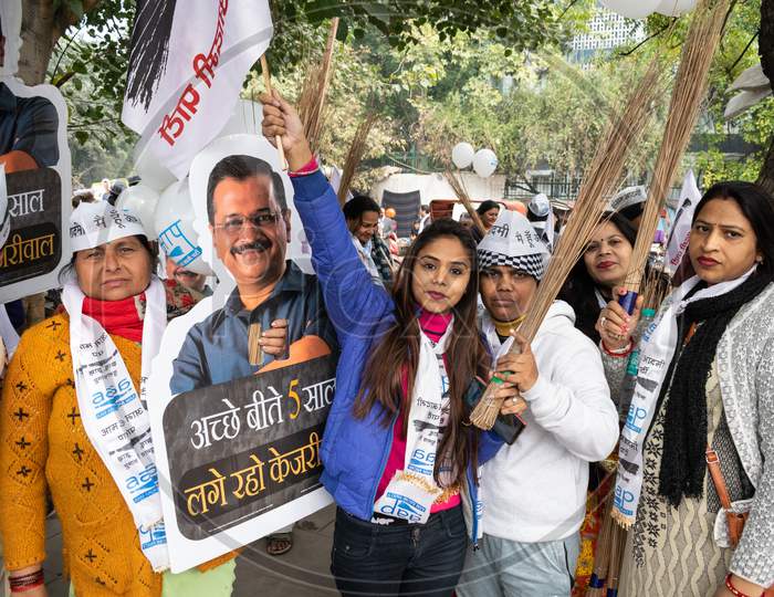Aam Aadmi Party AAP supporter holding cutout of Arvind Kejriwal, flag and AAP electoral symbol Broom during a rally for Delhi Assembly Election