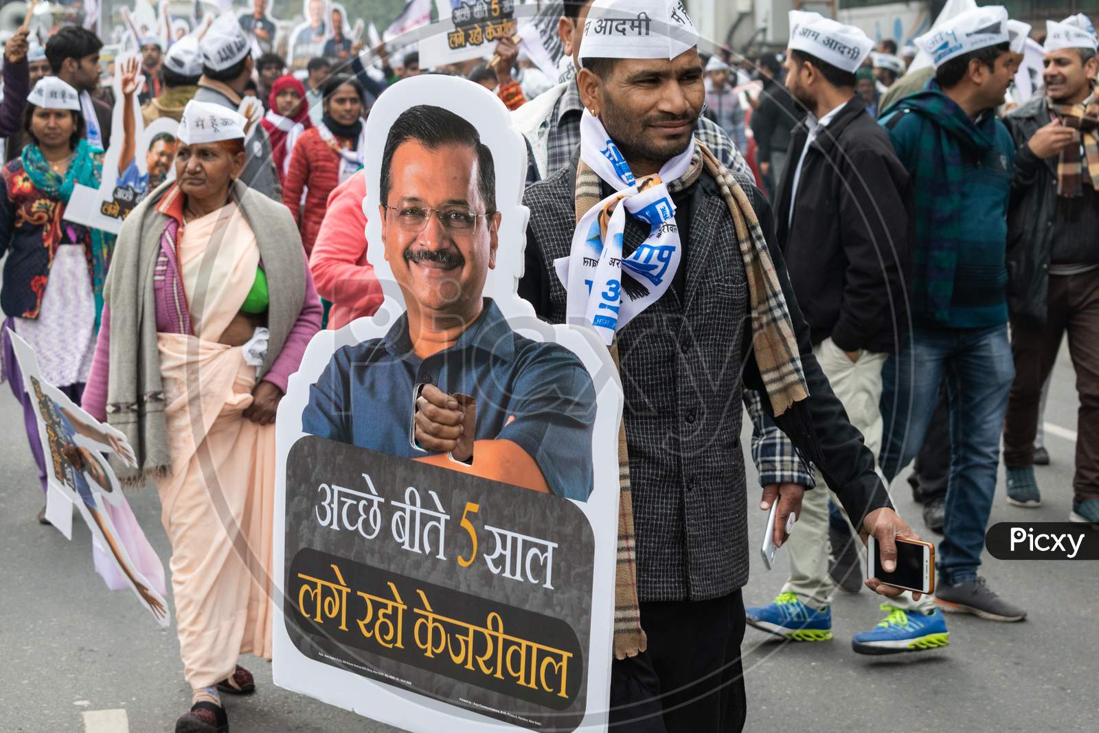 Aam Aadmi Party AAP supporter holding cutout of Arvind Kejriwal, flags and AAP electoral symbol Broom during a rally for Delhi Assembly Election