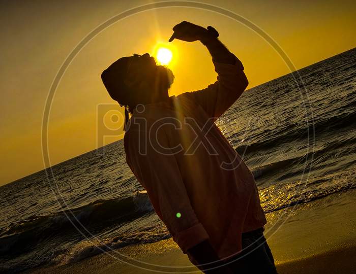 Silhouette Of Man At a Beach With Sunset Sun In Background