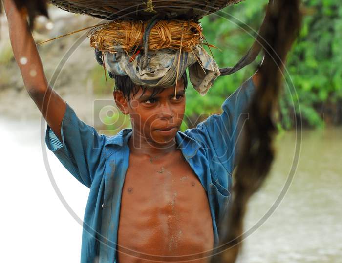 Indian little boy carrying a basket in the rain