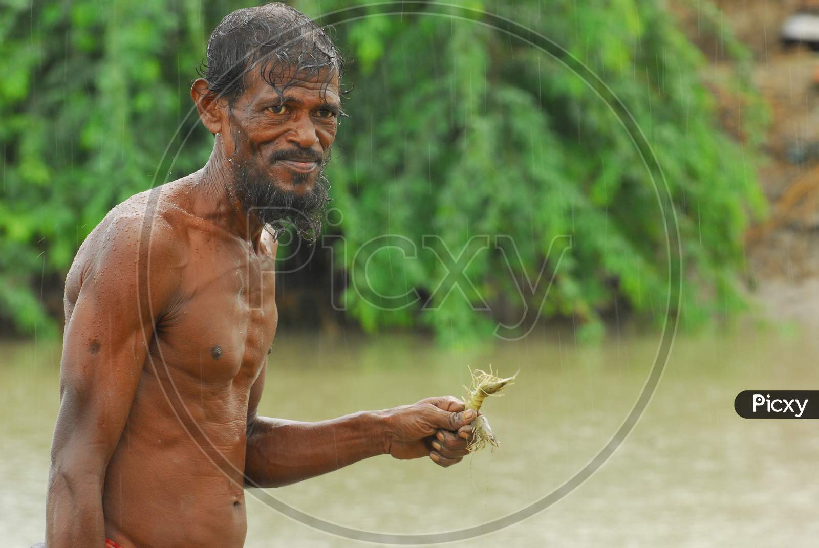 Indian fisherman smiling holding a shrimp