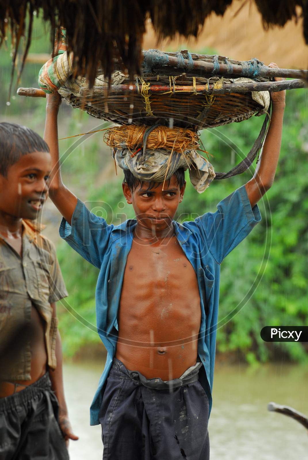 Indian little boy carrying a basket during rain