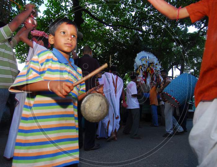 Indian little boy playing drums during visarjan