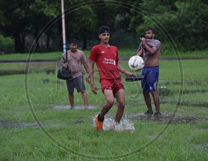 Indian boys playing football in the rain